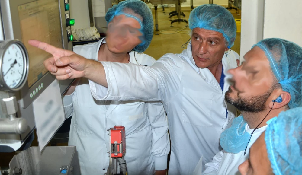 Alain FOURNIAL est avec 3 personnes (1 femme et 2 hommes) en pleine formation de cartographie autoclave devant la machine dans l'atelier de stérilisation. Tout le monde porte une blouse blanche et une charlotte bleue sur la tête